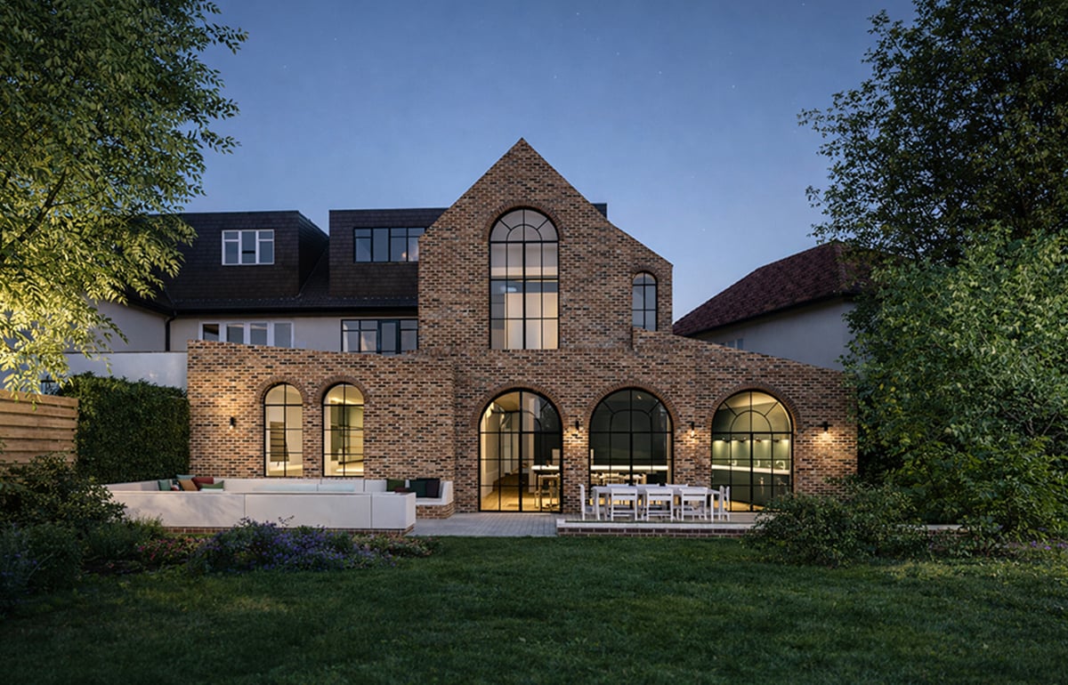 Evening view of a two-storey brick extension in West Hampstead featuring arched glazing and warm interior lighting, creating a strong connection between house and garden.