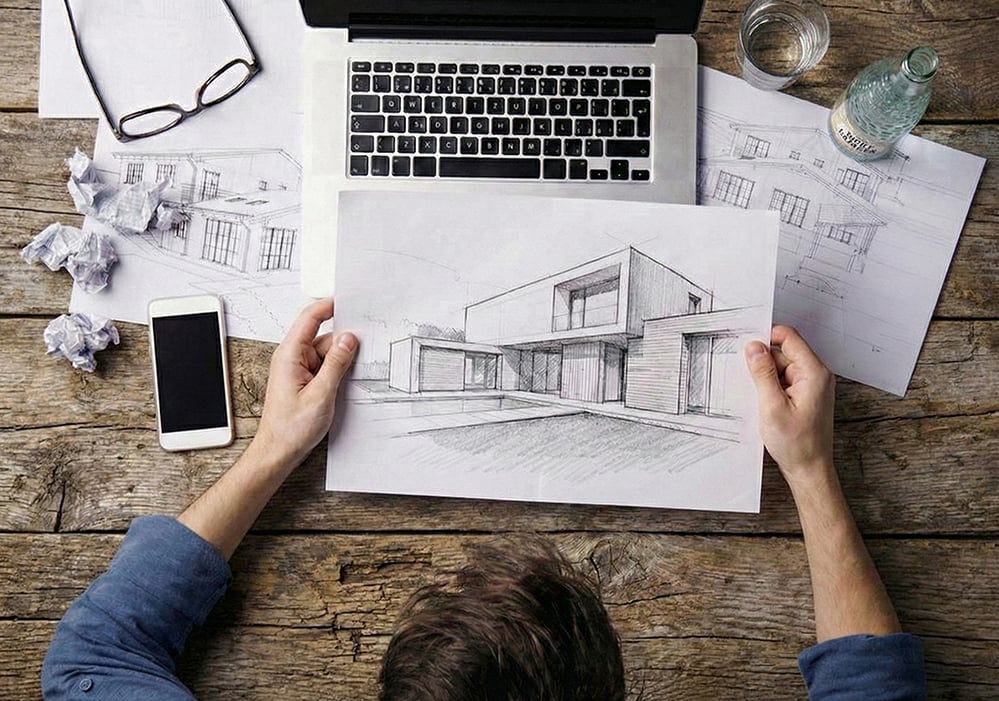 Architect reviewing hand-drawn architectural sketches alongside digital tools, illustrating a human-centred design process where AI supports creativity, technical decision-making and sustainable architecture outcomes.
