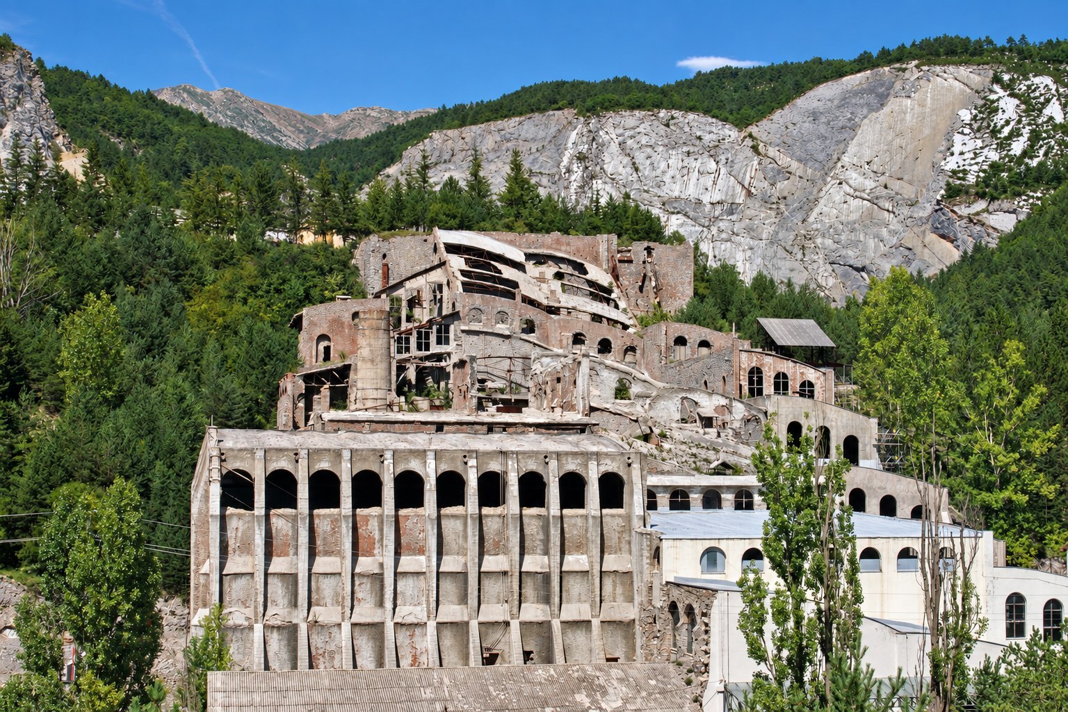 The ruined Asland cement factory at the Clot del Moro today, tiers of Rafael Guastavino's arched brick and cement vaults climbing the hillside, the lower level roofed in metal to house the Museu del Ciment, and the pale scar of the limestone quarry cut into the mountain behind. RISE Design Studio.