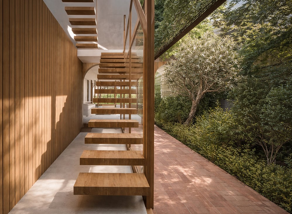 Timber-framed garden corridor with arched openings and climbing greenery, creating a seamless indoor-outdoor transition in a contemporary London residential extension with natural materials and filtered sunlight.