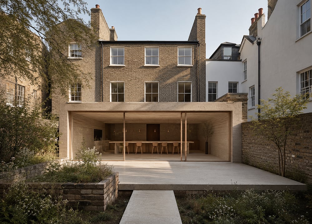 Contemporary rear extension to a Georgian brick house featuring large sliding glazing, natural materials and a landscaped garden. The design creates a clear distinction between old and new while improving daylight, garden connections and the home's overall performance.