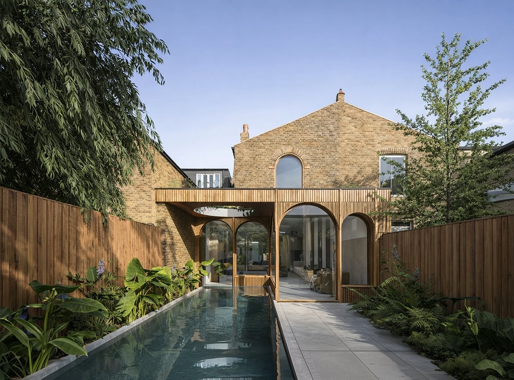 Glazed rear extension to a Victorian terraced house in London featuring sculpted timber arches, swimming pool and mature garden planting - illustrating high-specification house extension design and construction costs in London in 2026.