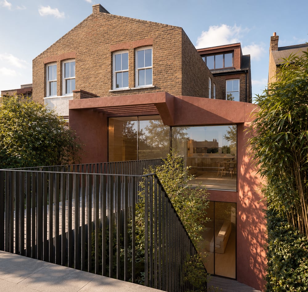 Rear view of Ribbon House on Chevening Road in Queen's Park, London, showing the AECB CarbonLite retrofit with a contemporary rear extension, deep louvred canopy for passive solar shading, large glazed family living space, planted basement lightwell, and high-performance low-energy design by RISE Design Studio.