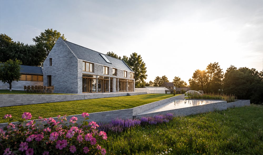 Sustainable new-build farmhouse with a pale stone gable form, large timber-framed glazing and a wildflower meadow and pond in open countryside