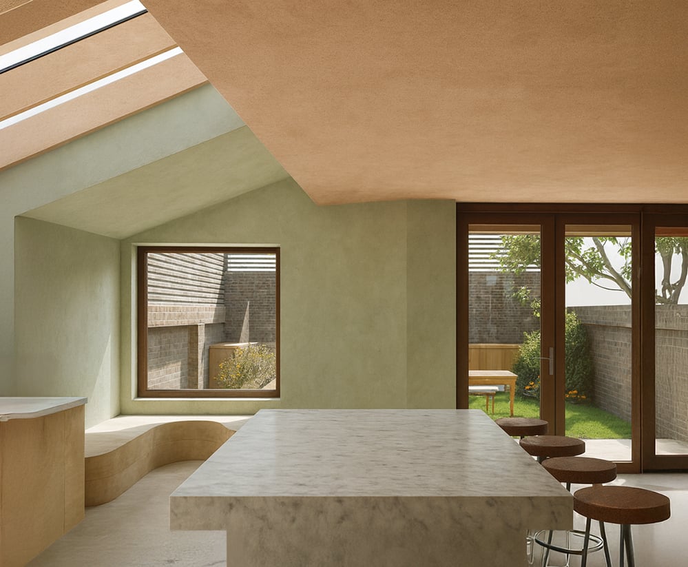 Kitchen-dining interior of the Rose Canopy House extension showing rooflights, timber structure, sculpted reveals and high-performance glazing that deliver natural light and passive comfort as part of the AECB-aligned retrofit.