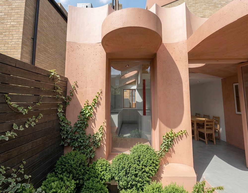 Close-up of curved pink lime render columns flanking a tall arched window, Scallop House Stoke Newington. Kitchen visible beyond. Victorian terrace extension by RISE Design Studio London.