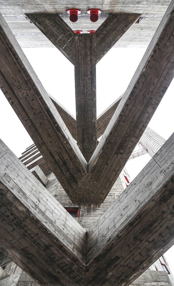 Upward view beneath Sesc Pompeia’s massive V shaped concrete beams, emphasising texture, scale and structural expression within Lina Bo Bardi’s brutalist architecture. Photo by Maria Gonzalez.