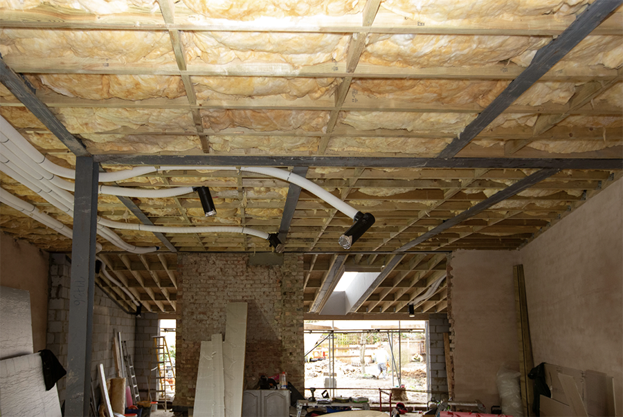 Exposed ceiling during retrofit by RISE Design Studio showing installed insulation and ventilation ductwork, designed to reduce overheating and improve indoor air quality as part of a sustainable, climate-resilient home upgrade.